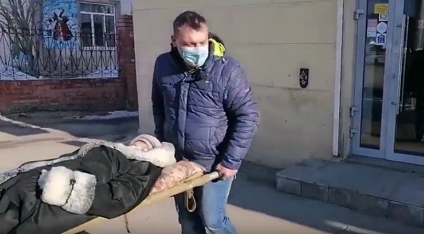 Родственники принесли в банк на носилках женщину со сломанной ногой